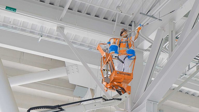 worker-on-lift-painting-cross-beams